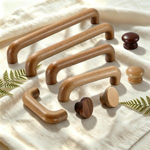 May include: A collection of wooden cabinet hardware including four arched handles of varying lengths and three round knobs in different wood tones. The hardware features smooth, rounded edges and natural wood grain patterns in light and dark brown.