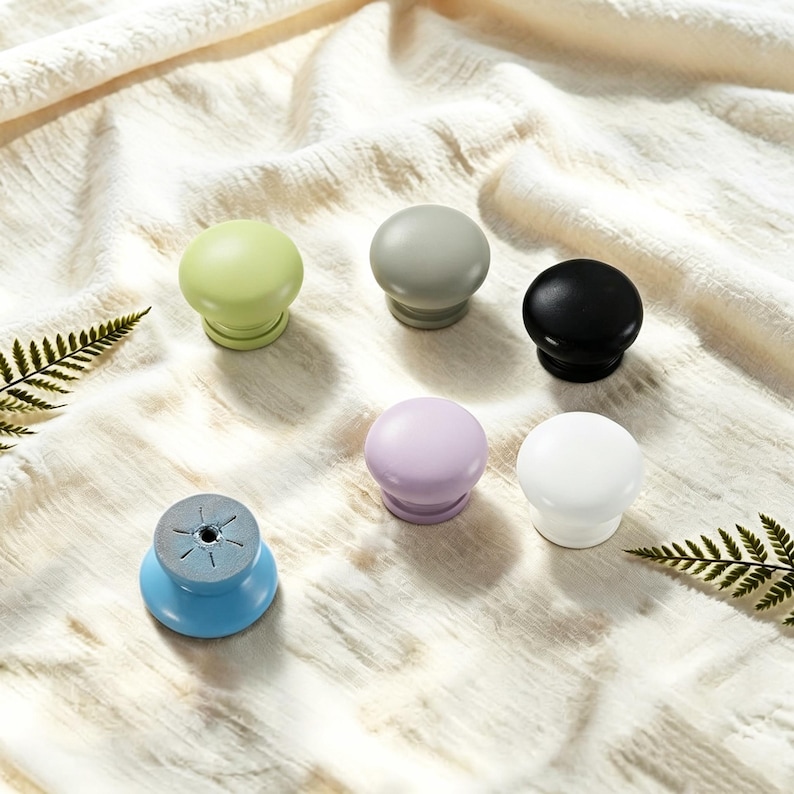Puede incluir: Una colecci&oacute;n de seis pomos redondos para armarios en varios colores s&oacute;lidos, incluyendo verde claro, verde salvia, negro, lavanda, blanco y azul. Cada pomo presenta una superficie superior lisa y redondeada y un orificio central de montaje.