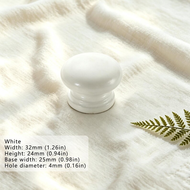 Puede incluir: Un pomo de mueble blanco liso y brillante con una parte superior redondeada y una base escalonada. Las dimensiones son 32 mm de ancho, 24 mm de alto, 25 mm de ancho de base y 4 mm de di&aacute;metro de orificio, seg&uacute;n el texto impreso.
