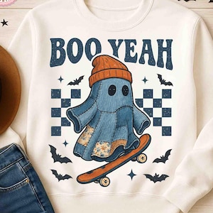Può includere: Felpa bianca con una grafica di un fantasma di jeans con un berretto arancione e uno skateboard. Il testo "BOO YEAH" è sopra il fantasma. Pipistrelli e stelle circondano il disegno, con un motivo a scacchi dietro il fantasma.