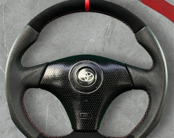 Volante personalizzato per Toyota Celica 1999-2005, con base piatta e rivestimento in pelle scamosciata nera.