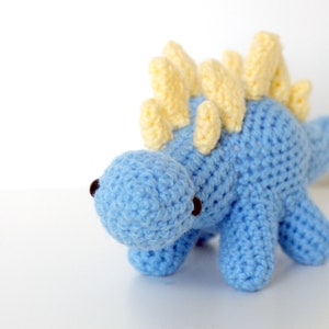 May include: A blue crocheted dinosaur toy with yellow spikes on its back.
