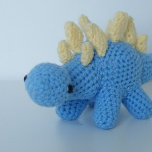 May include: A blue crocheted dinosaur toy with yellow spikes on its back.