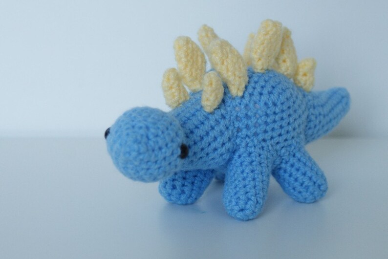 May include: A blue crocheted dinosaur toy with yellow spikes on its back.
