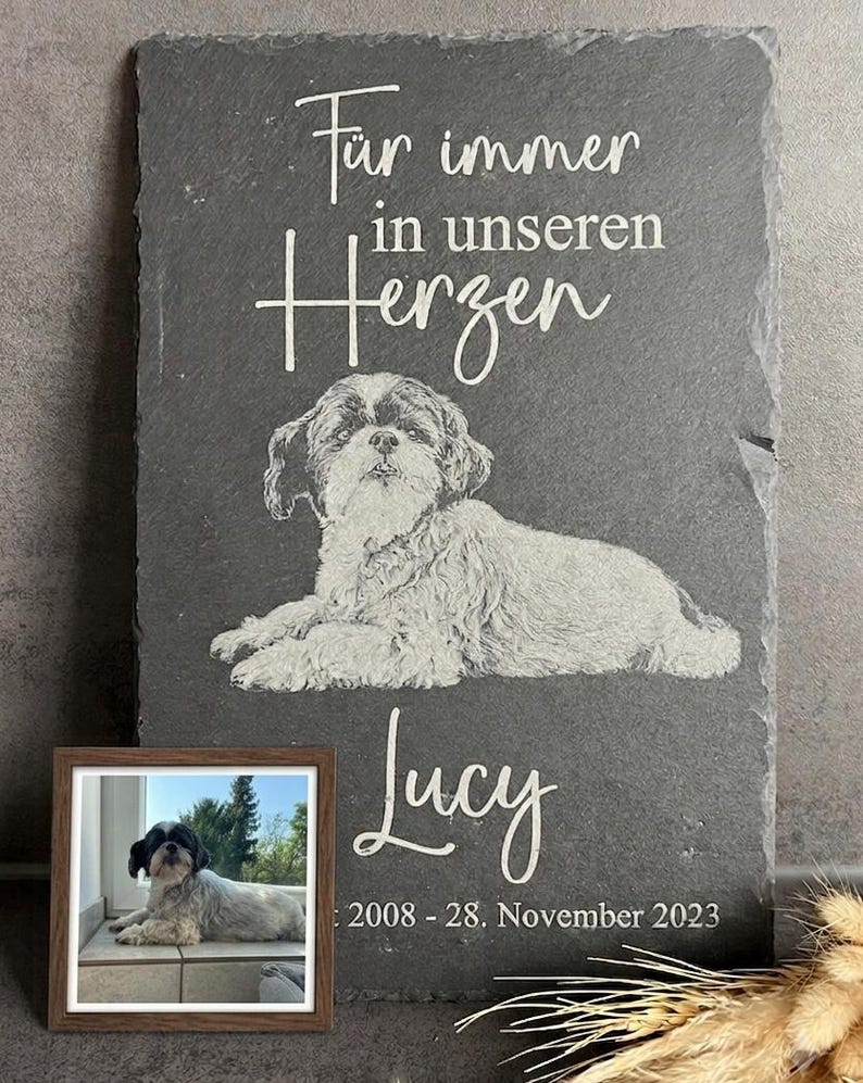 Puede incluir: Una placa rectangular de pizarra gris oscuro con el retrato grabado de un perro Shih Tzu. El texto dice "F&uuml;r immer in unseren Herzen", el nombre "Lucy" y las fechas "2008 - 28. November 2023". Incluye una peque&ntilde;a foto enmarcada.