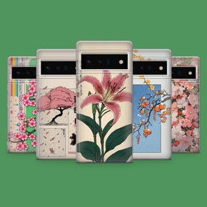 Può includere: Una collezione di custodie per telefoni con arte di ispirazione giapponese. I disegni includono un giglio rosa, fiori di ciliegio e un albero con foglie che cadono. Le custodie hanno un bordo color crema e un ritaglio per la fotocamera.