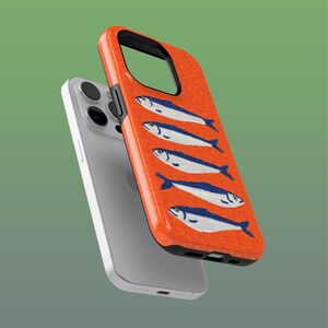 Peut inclure: Coque de téléphone orange avec un motif répété de poissons blancs et bleus stylisés. La coque est présentée avec un téléphone argenté, mettant en valeur le design et la protection. Un design original pour personnaliser un téléphone.