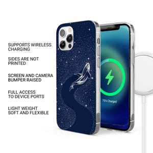 May include: A navy blue phone case with a white whale illustration against a starry background. The phone screen shows a charging symbol. The case supports wireless charging. The text on the case says: 'Supports Wireless Charging'.