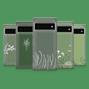 以下が含まれることがあります： オリーブグリーンの携帯電話ケース5つ。白い花のイラストが描かれています。ケースは、花と葉の白い植物画が特徴です。ケースは、無地の緑色の背景に並んでいます。