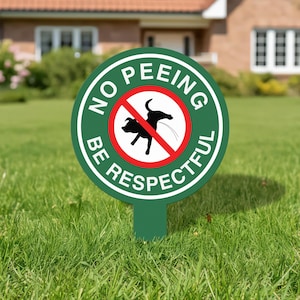 May include: A green circular sign with the words "NO PEEING BE RESPECTFUL" in white lettering. The sign features a red circle with a black silhouette of a dog urinating, crossed out with a red line. The sign is placed in a grassy yard.