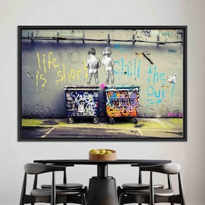 Può includere: Opera d'arte incorniciata con graffiti. Due figure urinano su colorati cassonetti. Il muro di sfondo presenta le frasi "life is short" e "chill the f*** out" in vernice spray gialla e blu.
