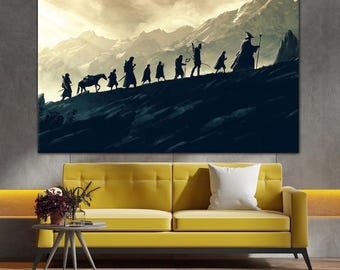 Op de afbeelding: Een canvas print met een silhouet van figuren die een berg beklimmen, met een paard in het midden. De achtergrond toont een bergketen onder een bewolkte hemel. Het kunstwerk wordt boven een gele bank weergegeven.