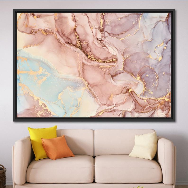 May include: Abstract art canvas print in a black frame. The artwork features a flowing design with shades of pink, gold, and blue. The canvas is displayed above a beige sofa with colorful throw pillows.