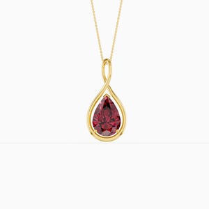 May include: A gold pendant necklace featuring a pear-shaped, deep red gemstone. The gemstone is set in a gold bezel within a teardrop-shaped frame, suspended from a delicate gold chain. The design is simple and elegant.