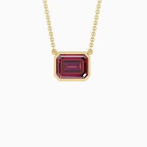Puede incluir: Un collar dorado con un colgante rectangular de piedra preciosa rojo intenso. El colgante está engastado en un bisel dorado y cuelga de una delicada cadena dorada. La piedra preciosa tiene una superficie facetada, que refleja la luz.