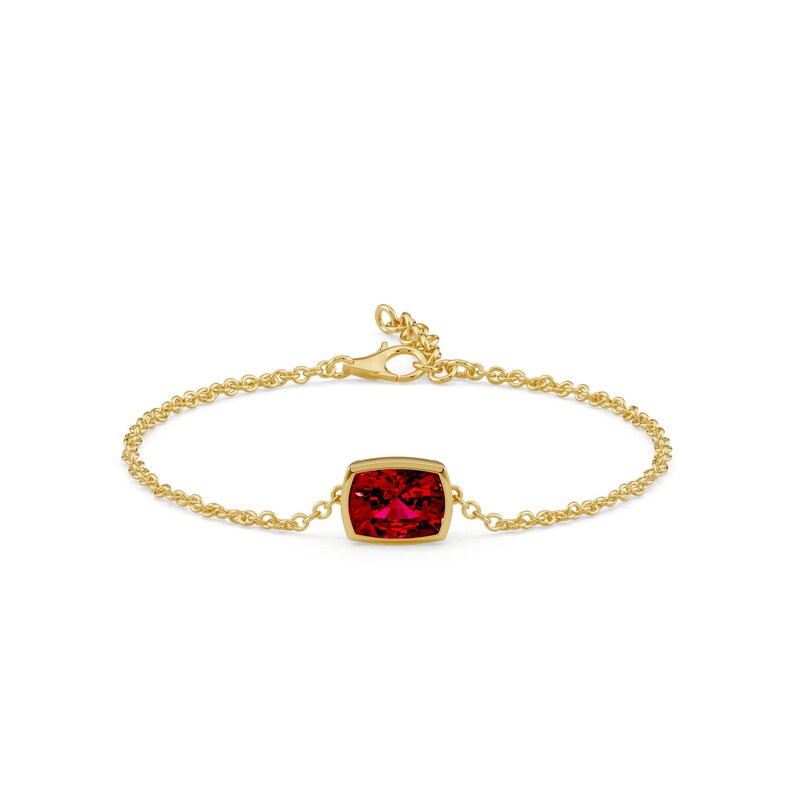 K&ouml;nnte beinhalten: Ein goldenes Armband mit einem leuchtend roten Edelstein. Der Edelstein ist rechteckig mit abgerundeten Ecken und in einer goldenen Fassung gefasst. Das Armband hat eine feine Kette und einen Verschluss.