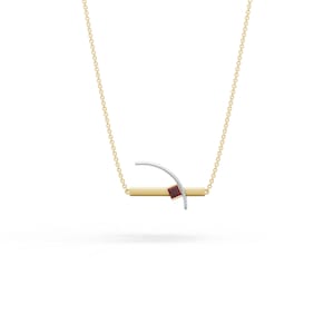 Puede incluir: Un collar de cadena dorada con un colgante de barra horizontal dorada cruzado por un arco plateado curvo. Una pequeña piedra preciosa de color rojo oscuro y corte cuadrado está engastada donde la barra dorada y el arco plateado se encuentran.