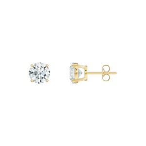 May include: A pair of stud earrings featuring a round, clear gemstone set in a gold-colored metal. One earring is shown face-on, and the other is shown from the side, displaying the post and butterfly backing.