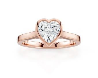 Op de afbeelding: Een roségouden ring met een hartvormige diamant. De diamant is gezet in een bezel setting, en de band heeft een gepolijst ontwerp. Een klassiek en elegant sieraad.