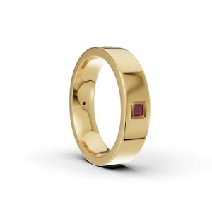 May include: A polished yellow gold band featuring a single square-cut deep red gemstone set flush into the outer surface. The ring has a smooth, wide profile with a reflective metallic finish and a clean, uniform design throughout the band.