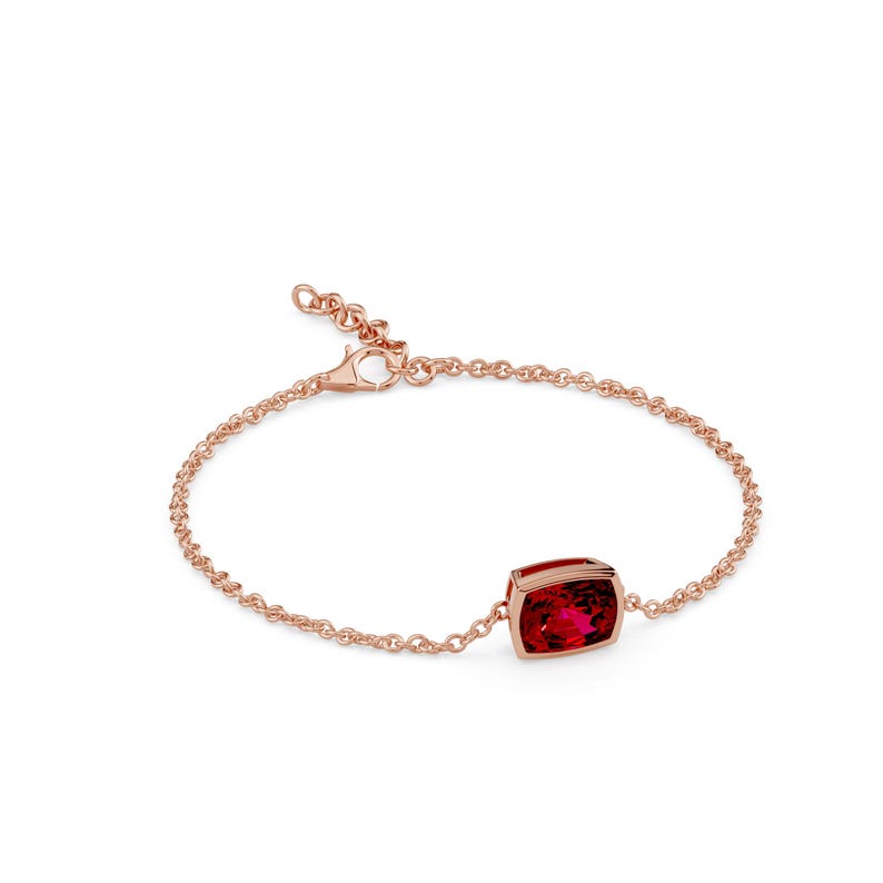 K&ouml;nnte beinhalten: Ein ros&eacute;goldenes Armband mit einem rechteckigen, tiefroten Edelstein. Der Edelstein ist in einer L&uuml;nettenfassung gefasst und bildet den Mittelpunkt des zarten Kettenarmbands. Das Armband hat einen Karabinerverschluss.