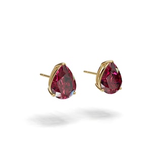 May include: A pair of stud earrings featuring pear-shaped, deep red gemstones set in gold-colored metal. The gemstones are faceted, catching the light. The earrings are displayed against a white background.