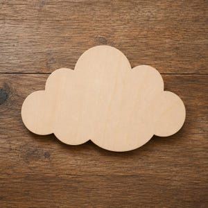 Puede incluir: Recorte de madera con forma de nube, de color marrón claro, sobre una superficie de madera marrón oscuro. La nube tiene un aspecto liso y sin terminar, con bordes redondeados y un diseño sencillo. Ideal para manualidades y proyectos de bricolaje.