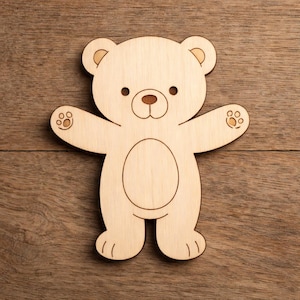 Könnte beinhalten: Aus Holz gefertigte Bär-Form mit ausgestreckten Armen, mit gravierten Details für Augen, Nase, Mund und Pfoten. Der hellbraune Bär steht auf einer Holzoberfläche.