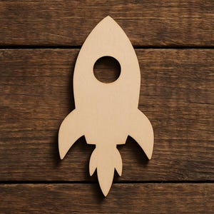 May include: A light brown wooden rocket ship cutout with a circular window and stylized fins. The rocket is set against a dark brown wooden background. This craft is ideal for crafting projects or as a decorative element.