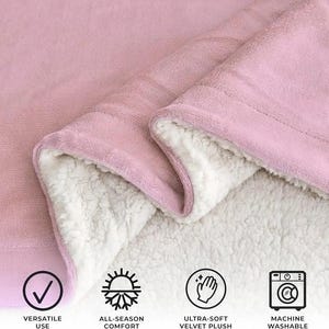 K&ouml;nnte beinhalten: Eine rosa Decke mit einer weichen, pl&uuml;schigen Au&szlig;enseite und einer wei&szlig;en, flauschigen Innenseite. Die Decke ist gefaltet, um die kontrastierenden Texturen zu zeigen. Das Bild enth&auml;lt Symbole, die vielseitige Verwendung, Ganzjahreskomfort, ultraweiches Samtpl&uuml;sch und Maschinenw&auml;sche anzeigen.