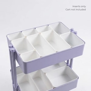May include: A set of white plastic storage inserts organized within a light purple tiered utility cart. The inserts are rectangular and square, designed to fit into the cart shelves. Text in the upper right corner reads: Inserts only Cart not included.