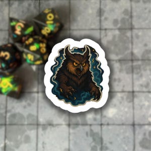 Puede incluir: Una pegatina con una ilustración detallada de un búho con plumas marrones y amarillas, un pico abierto y ojos amarillos penetrantes. El búho está rodeado por un borde ondulado azul y blanco con acentos de rayos. Dados en el fondo.