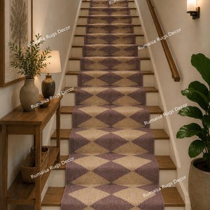 May include: A long stair runner rug featuring a repeating diamond pattern in muted purple and beige tones. The runner is centered on wooden stairs and finished with a fringe at the bottom edge. The text Rumaisa Rugs Decor appears on the image.