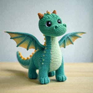 Könnte beinhalten: Ein handgehäkelter Drache in Türkis, Grün und Gelb. Der Drache hat große, schwarze Augen, kleine Hörner und detaillierte Flügel. Der Körper ist eine Mischung aus Türkis und Hellgrün, mit gelben Akzenten. Ein verspieltes, weiches Spielzeug.