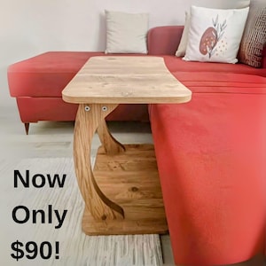 Könnte beinhalten: Ein Beistelltisch aus Holz mit geschwungenem Bein-Design. Der Tisch hat eine hellfarbene Tischplatte und ein unteres Regal. Der Text "Now Only $90!" wird im Bild angezeigt.