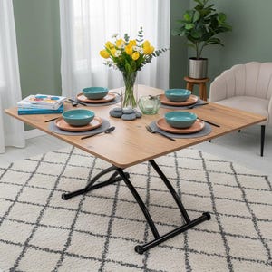 May include: A square wooden dining table with a black metal base, set for four. Each place setting includes a teal bowl, a coral plate, and silverware on a gray placemat. A vase of yellow tulips and daisies sits in the center.