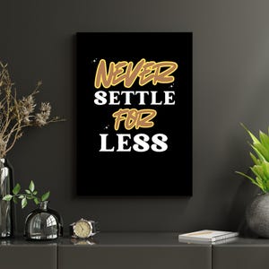May include: A black framed wall art print with the words "NEVER SETTLE FOR LESS" in white and gold lettering. The artwork is displayed on a dark gray wall, with decorative items in the foreground.