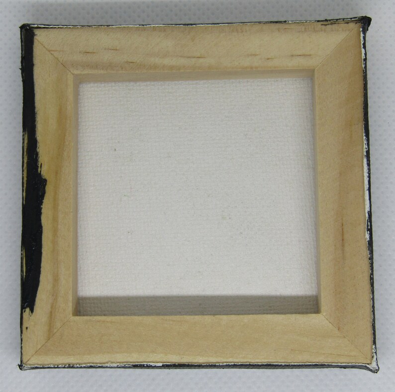 Puede incluir: Un peque&ntilde;o marco de madera para lienzo con un lienzo blanco estirado en su interior. El marco est&aacute; pintado de negro en los bordes.