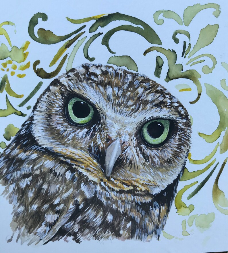 A bright green eyed owl peers out. light decoration in the background.
