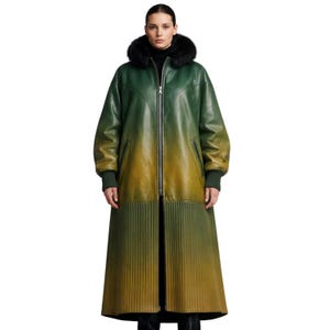 Può includere: Un lungo cappotto in pelle verde e giallo sfumato con cappuccio foderato in pelliccia nera. Il cappotto ha una chiusura con cerniera, polsini a coste e una gonna a pieghe. La modella indossa un dolcevita nero.
