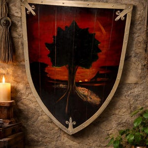 May include: A wooden shield with a painted landscape scene. The shield features a black tree silhouette against a red and orange sunset. The shield has a metal trim and decorative accents.