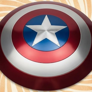 K&ouml;nnte beinhalten: Ein runder Schild in Rot, Silber und Blau. Er hat einen zentralen blauen Kreis mit einem wei&szlig;en Stern, umgeben von silbernen und roten Ringen. Dieser Schild ist eine Nachbildung von Captain Americas Schild.
