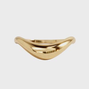 May include: A polished gold ring featuring a smooth, curved V-shape design. The band has a continuous, rounded surface with a high-shine metallic finish that reflects light across its contoured, undulating form, creating a sleek, solid appearance.