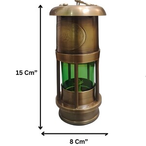 Op de afbeelding: Een vintage messing lantaarn, 15 cm hoog en 8 cm breed, met een groene glazen behuizing. De lantaarn heeft een ronde boven- en onderkant en een handvat. De tekst "ROYAL NAVY" is zichtbaar op de zijkant.