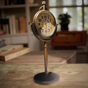 Puede incluir: Un reloj de escritorio de latón de estilo vintage con esfera redonda. El reloj tiene una esfera color crema con números y manecillas negras. El reloj está sostenido por un soporte vertical y una base circular. La esfera del reloj tiene aproximadamente 10 cm de diámetro.