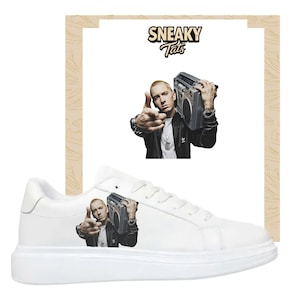 May include: White sneakers with a thick sole. The side of the shoe features a graphic of a man holding a boombox. The image also includes a larger image of the same man and boombox. The text "Sneaky Tats" is at the top.