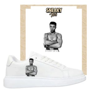 Könnte beinhalten: Weiße Sneaker mit einem Schwarz-Weiß-Bild von Muhammad Ali auf der Seite. Die Sneaker haben eine dicke weiße Sohle und ein klassisches Schnürdesign. Das Bild von Ali zeigt ihn mit verschränkten Armen. Der Markenname "Sneaky Tats" befindet sich oben.