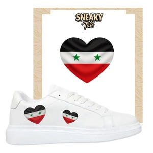 May include: White trainers with a heart-shaped design in the colours of the Syrian flag. The trainers have a thick white sole and the text "Sneaky Tats" is visible in the background.