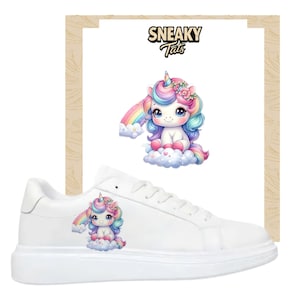 May include: White trainers featuring a colourful unicorn design. The unicorn has a rainbow mane and tail, and sits on a cloud. The text "Sneaky Tats" is above the unicorn image.