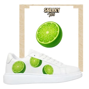 May include: White sneakers with lime slice graphics. The shoes have a white sole and upper, with three green lime slice designs on the side. The top of the image has a lime slice graphic and the text "Sneaky Tats".